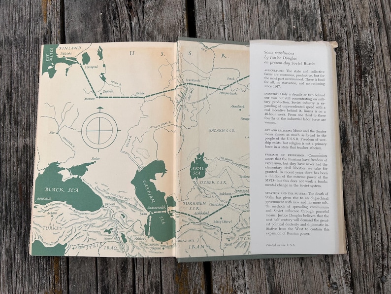 May include: An open book with a cream-coloured map of the U.S.S.R. featuring dark green bodies of water and dashed travel lines. The right page contains a white dust jacket flap with black printed text titled Some conclusions by Justice Douglas.