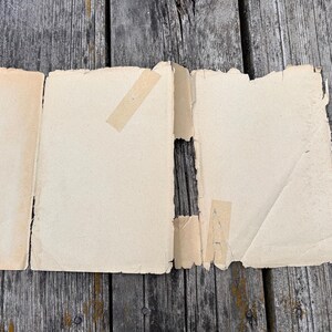 May include: A detached, cream-coloured paper book jacket with frayed edges and visible adhesive tape strips, positioned next to a blue hardcover book with the text "Sally of the Girl Orchestra" printed in orange on the spine.