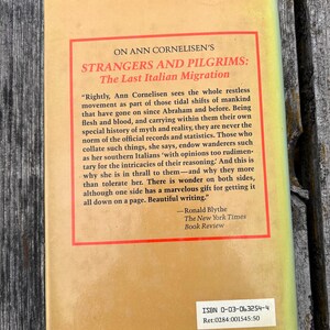 May include: The back cover of a book titled Strangers and Pilgrims: The Last Italian Migration by Ann Cornelisen. It features a tan background with a red-bordered text box containing a review by Ronald Blythe and an ISBN 0-03-063254-4 label.