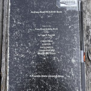 May include: A black, rectangular book cover with white text reading An Easy-Read HOLIDAY Book, Titles in the Easy-Read Holiday Book Series by Cass R. Sandak, CHRISTMAS, EASTER, HALLOWEEN, THANKSGIVING, VALENTINE'S DAY, and A Franklin Watts Library Edition.