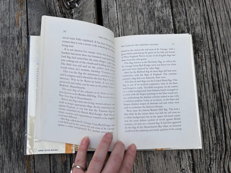 May include: An open hardcover book with white pages and black printed text. The left page is numbered 30 and titled The Story of Old Glory, while the right page is numbered 31 and titled The Flags of the Thirteen Colonies.