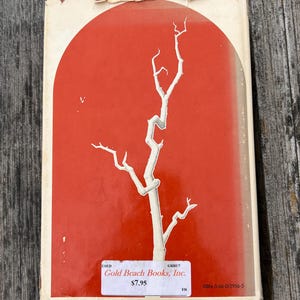 May include: A rectangular book cover featuring a vibrant orange background with a large, white, arched graphic containing a stylized white tree branch. A white rectangular sticker displays the text Gold Beach Books, Inc. and ISBN: 0-06-012956-5.