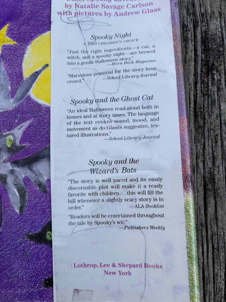 K&ouml;nnte beinhalten: Ein Buchcover mit violettem Hintergrund, einem gelben Mond und schwarzen Fledermausillustrationen. Der Text enth&auml;lt die Titel Spooky Night, Spooky and the Ghost Cat und Spooky and the Wizard's Bats sowie Rezensionen und den Verlagsnamen.