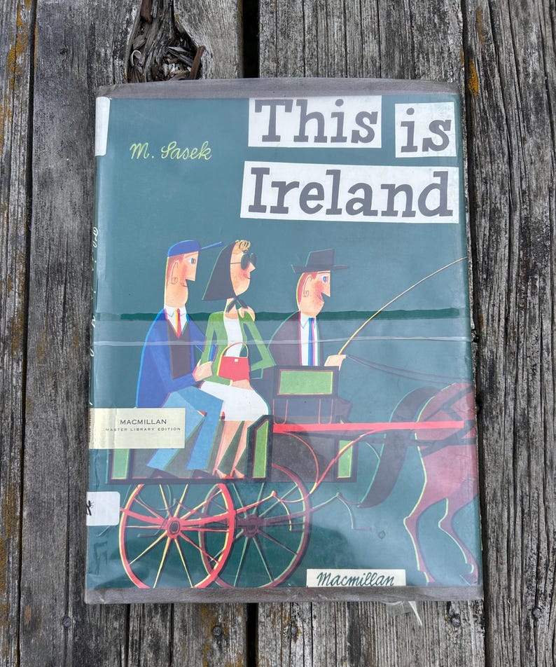 Peut inclure: Un livre reli&eacute; intitul&eacute; This is Ireland par M. Sasek, pr&eacute;sentant une couverture verte avec une illustration stylis&eacute;e de trois personnes dans une cal&egrave;che tir&eacute;e par un cheval. Le logo Macmillan Master Library Edition est visible.