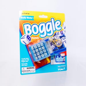 May include: A Boggle keychain game in its original yellow and blue packaging. The set includes a small blue grid with sixteen letter cubes, a removable mini timer, and a metal keyring. The packaging features the Boggle logo and text.