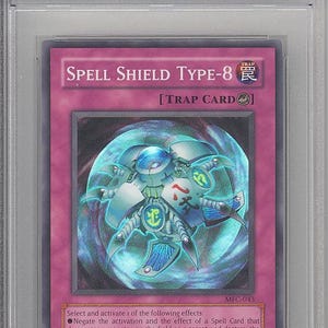 May include: A 2003 Yu-Gi-Oh! Magician Force Spell Shield Type-8 trading card, graded Mint 9 by PSA. The card features a purple background with a central blue mechanical creature inside a glowing orb, with text detailing trap card effects.