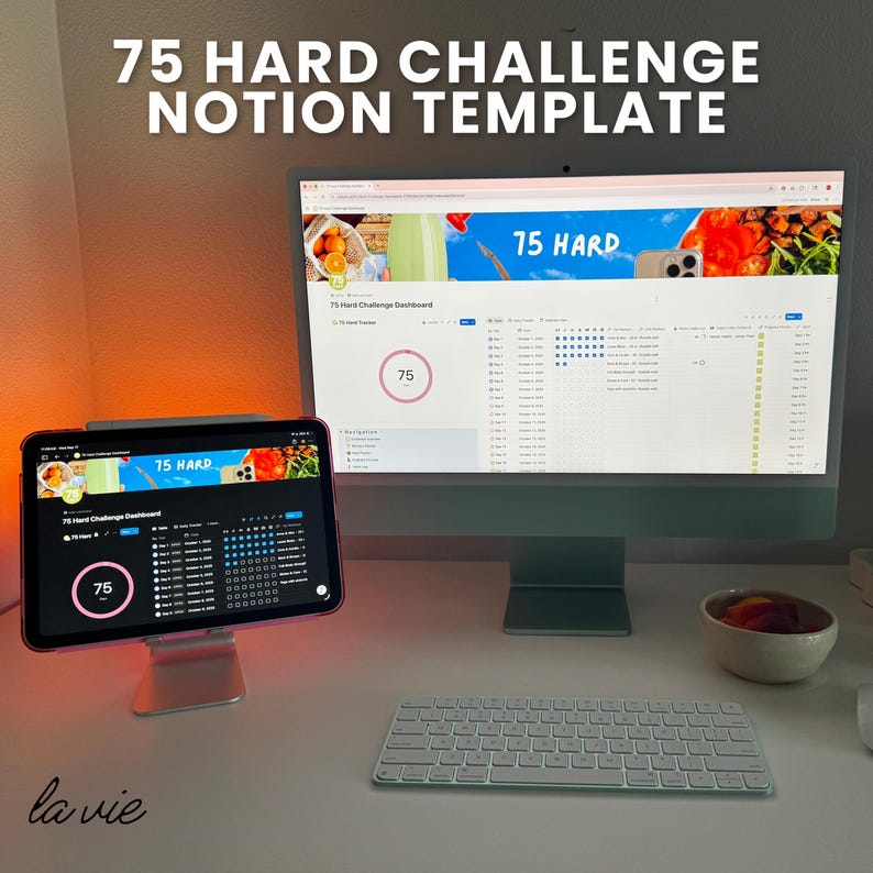 May include: A workspace setup featuring a desktop computer and a tablet displaying a "75 Hard Challenge Notion Template." The computer and tablet screens show a dashboard with progress tracking. A white keyboard and a small bowl are also visible.
