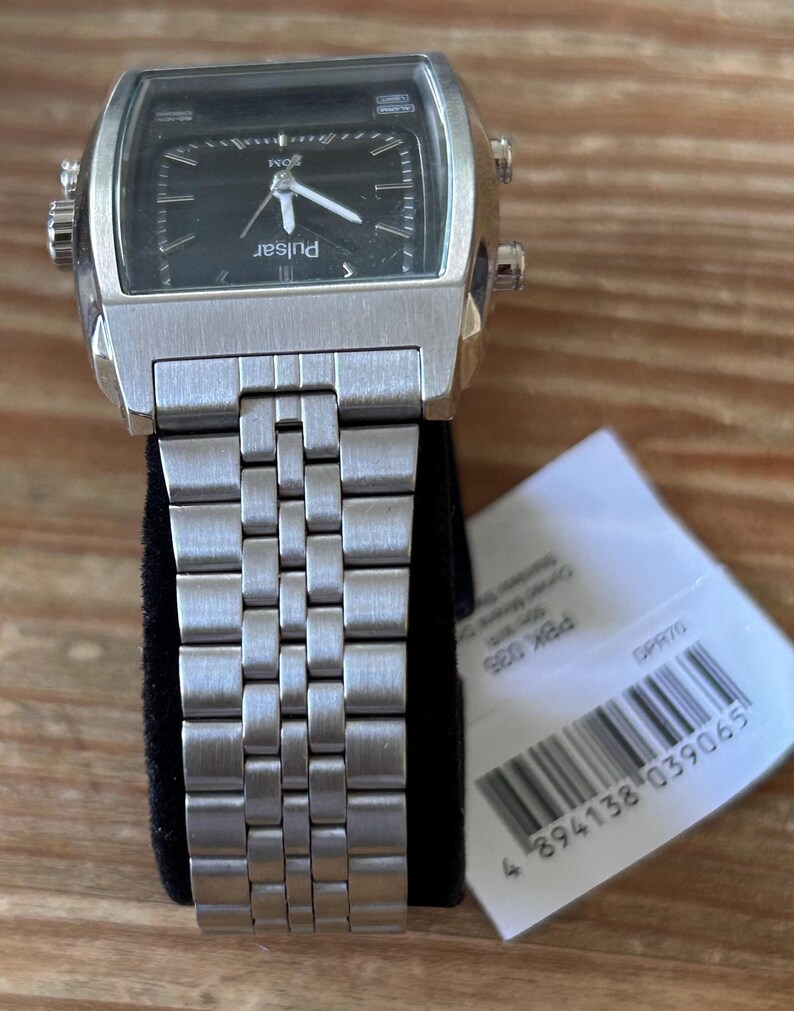 May include: A silver Pulsar watch with a rectangular black face and a metal strap. The watch has a square face with white hands and markers. The brand name "Pulsar" is printed on the watch face.