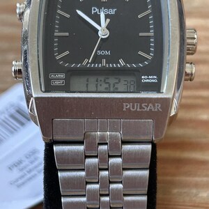 May include: A silver-coloured Pulsar watch with a rectangular black face. The watch has a digital display showing the time, alongside analogue hands. The watch strap is made of silver-coloured metal. The watch face has the word "Pulsar" printed on it.