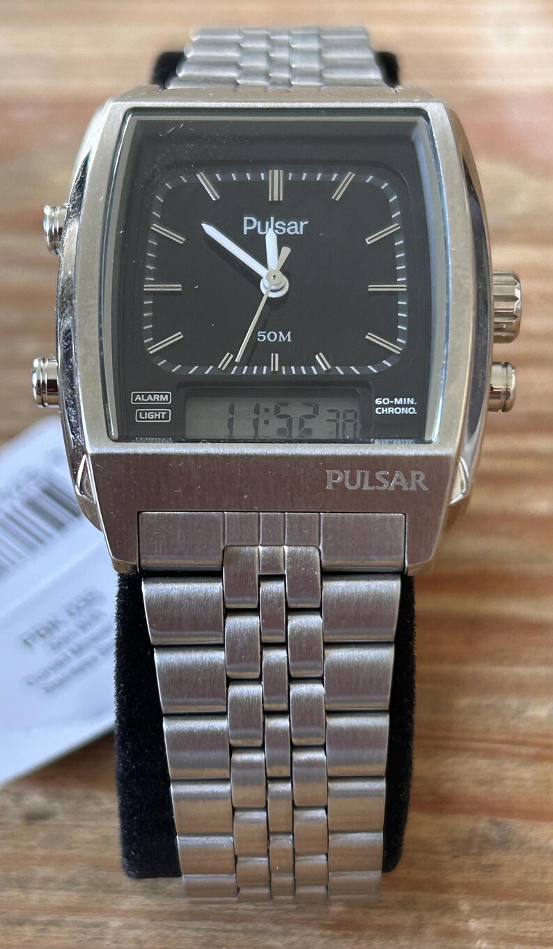 May include: A silver-coloured Pulsar watch with a rectangular black face. The watch has a digital display showing the time, alongside analogue hands. The watch strap is made of silver-coloured metal. The watch face has the word "Pulsar" printed on it.