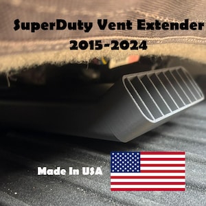 May include: A black SuperDuty Vent Extender for 2015-2024 models. The product is made in the USA and features a slotted vent design. The image shows the product installed under a vehicle's interior.