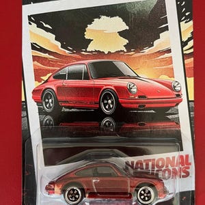 May include: Hot Wheels Silver Series die-cast car of a red '67 Porsche 911 R. The packaging features a retro design with the words "National Icons" and "Hot Wheels Silver Series". The car is a 1:64 scale model.