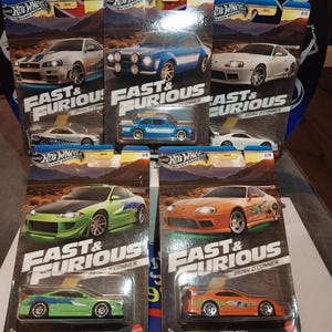 May include: A collection of Hot Wheels die-cast toy cars from the "Fast & Furious" series. The cars are in their original packaging, featuring various models like the Toyota Supra and Mitsubishi Eclipse. The packaging includes the "Hot Wheels" and "Fast & Furious" logos.