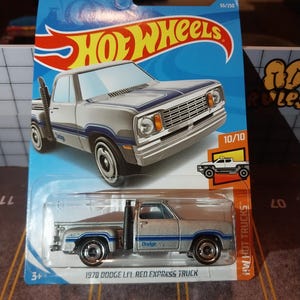 Puede incluir: Un coche de juguete Hot Wheels de fundición a presión, un Dodge Li'l Red Express Truck de 1978. El coche es plateado con rayas y detalles azules, un tubo de escape negro y el logotipo de Hot Wheels.