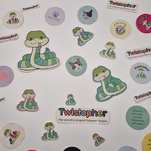 Może przedstawiać: Kolekcja kolorowych naklejek z postacią węża z kreskówki o imieniu "Twistopher". Naklejki zawierają różne wzory, takie jak wąż, twarze kotów i tekst, np. "Artist of work" i "Can't go out, My yarn needs me."