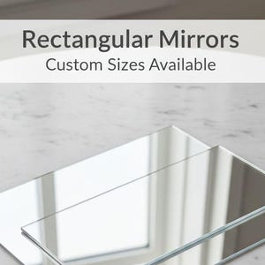 Può includere: Due specchi rettangolari sono impilati su una superficie di marmo. La parte superiore dell'immagine contiene il testo "Rectangular Mirrors" e "Custom Sizes Available". Gli specchi sono trasparenti e riflettono l'ambiente.