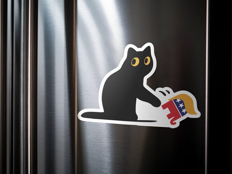 Puede incluir: Una pegatina de gato negro con ojos amarillos, sosteniendo un elefante de dibujos animados con un dise&ntilde;o rojo, blanco y azul. La pegatina est&aacute; en la puerta plateada de una nevera.