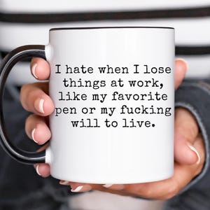 Op de afbeelding: Witte keramische mok met een zwart handvat en rand. De mok heeft de tekst: "I hate when I lose things at work, like my favorite pen or my fucking will to live."