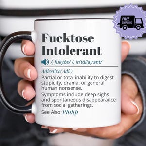 Può includere: Tazza in ceramica bianca con manico e bordo neri, con la scritta "Fucktose Intolerant" in nero. La tazza include una definizione della parola e un adesivo "Spedizione gratuita".