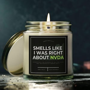 Puede incluir: Una vela blanca con una etiqueta negra que dice "Smells like I was right about NVDA". La vela está encendida y la llama es visible.