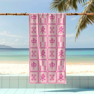 K&ouml;nnte beinhalten: Rosafarbenes Strandtuch mit einem sich wiederholenden Muster aus chinesischen Mahjong-Steinen. Die Steine ​​tragen die Zeichen "中", "東" und "發".