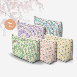 May include: Five zippered cosmetic bags in various colors, each adorned with a repeating pattern of Chinese characters and symbols. The bags are in shades of green, pink, yellow, blue, and purple, with gold-colored zippers.