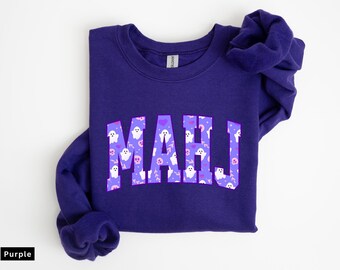 Puede incluir: Sudadera morada con la palabra "MAHJ" en letras decoradas con fantasmas, calaveras y corazones blancos y morados. La sudadera tiene cuello redondo.