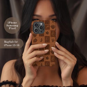 May include: A brown phone case with a repeating pattern of seashells, starfish, and other sea-themed designs. The case is held up in front of a person's face. Text on the left side reads "iPhone Samsung Pixel" and "MagSafe for iPhone 13-16."