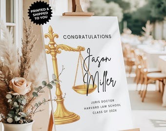 May include: A white graduation sign on an easel with gold detailing. The sign reads "Congratulations Jason Miller, Juris Doctor, Harvard Law School, Class of 202X." A gold scale of justice is featured on the sign.