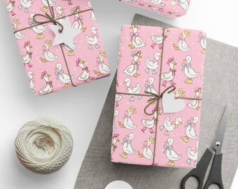 May include: Pink gift boxes wrapped in paper with a repeating pattern of cartoon geese wearing bows and boots. The gifts are tied with twine and adorned with white paper tags. A ball of twine and scissors are also visible.