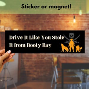 May include: Black and white sticker or magnet with the text "Drive It Like You Stole It from Booty Bay". A pirate skull with crossed swords and a pirate with two dogs and a dwarf are depicted in orange.