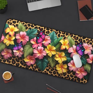 May include: A rectangular mouse pad featuring a leopard print background. The pad is decorated with colorful hibiscus flowers, green leaves, and butterflies. A white computer mouse rests on the pad.