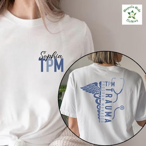 May include: A white ceramic mug with a black handle and the text "But First, Coffee" in a bold, black font. The mug is filled with a dark liquid, likely coffee, and sits on a light-colored surface.