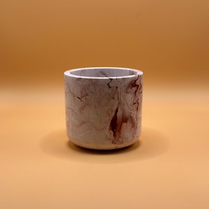 May include: A white ceramic planter with a marbled design in shades of pink and brown.