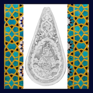 May include: A silver pendant with an intricate design featuring a seated figure with a crown and floral motifs. The pendant is surrounded by a border of geometric patterns.
