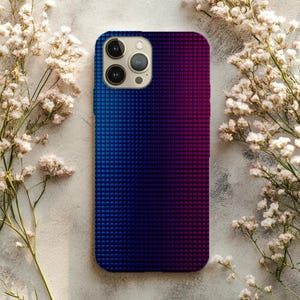 May include: A smartphone case with a gradient design, transitioning from blue to purple. The case has a textured, dotted pattern and a camera module with three lenses. White flowers are arranged around the case.