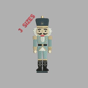 May include: An embroidered image of a toy nutcracker soldier in a blue uniform with gold accents, a black hat, and black boots. The text "3 SIZES" is in red. The nutcracker has a white mustache and eyebrows, and a red mouth.