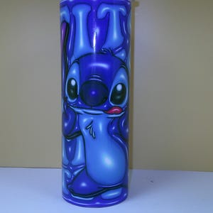 Puede incluir: Un vaso azul con un personaje de dibujos animados. El personaje tiene ojos grandes, una nariz grande y una lengua que sobresale. El vaso es cil&iacute;ndrico y tiene un acabado brillante. El dise&ntilde;o es de un azul vibrante.