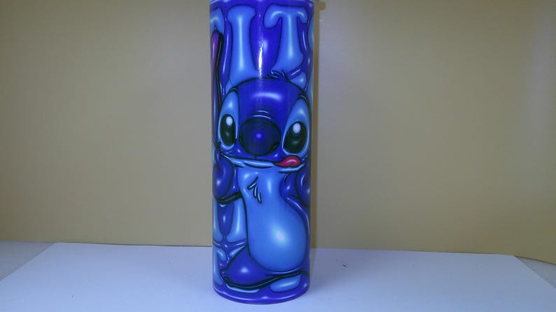 Puede incluir: Un vaso azul con un personaje de dibujos animados. El personaje tiene ojos grandes, una nariz grande y una lengua que sobresale. El vaso es cil&iacute;ndrico y tiene un acabado brillante. El dise&ntilde;o es de un azul vibrante.