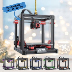 May include: A black and red 3D printer ornament with the name "JACOB" on the base. The ornament is flat, not 3D, and is suspended by a gold string. Below are five additional ornaments with different colored accents, each with the name "JACOB".