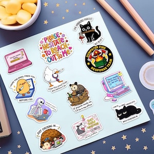 a collection of colorful stickers with various cartoon-style illustrations, including a cat, a bird, a laptop, and other whimsical objects. The stickers are arranged on a white background, with some placed on a desk and others on a table.