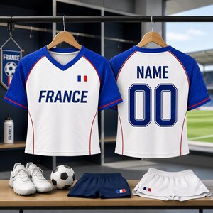A pair of France national soccer team uniforms, including a jersey and shorts, are displayed on a rack.