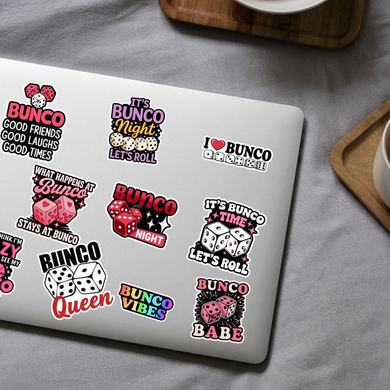 May include: A collection of colorful Bunco-themed stickers on a laptop. The stickers feature dice, hearts, and phrases like "Bunco Night," "Let's Roll," and "Bunco Babe." The color palette includes pink, red, black, and white.