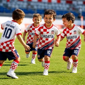 A group of young boys in red and white Croatia soccer uniforms are running and smiling on a soccer field.