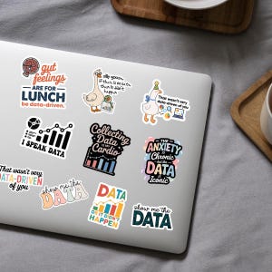 Puede incluir: Una colecci&oacute;n de pegatinas coloridas con temas relacionados con datos se muestra en una computadora port&aacute;til. Las pegatinas presentan frases como "I Speak Data", "Collecting Data is My Cardio" y "Show Me the Data". Otras pegatinas tienen im&aacute;genes de pizza, gansos y gr&aacute;ficos.