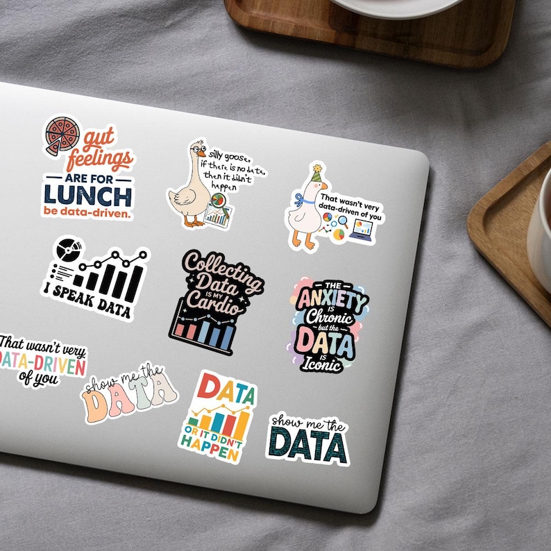 Puede incluir: Una colecci&oacute;n de pegatinas coloridas con temas relacionados con datos se muestra en una computadora port&aacute;til. Las pegatinas presentan frases como "I Speak Data", "Collecting Data is My Cardio" y "Show Me the Data". Otras pegatinas tienen im&aacute;genes de pizza, gansos y gr&aacute;ficos.