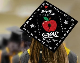 May include: Black graduation cap with the text "Helping little minds grow" and an apple graphic. The cap also includes the text "School Name" and "Your Name". The edges of the cap are decorated with the letters of the alphabet.