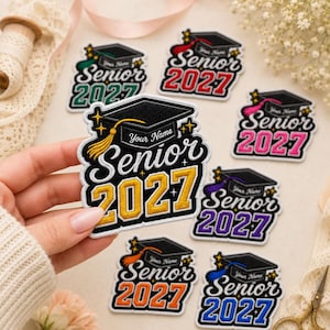 May include: A collection of embroidered patches featuring a black graduation cap with a tassel and the text "Senior 2027" with "Your Name" above it. The patches come in various accent colors including gold, red, pink, purple, orange, green, and blue.