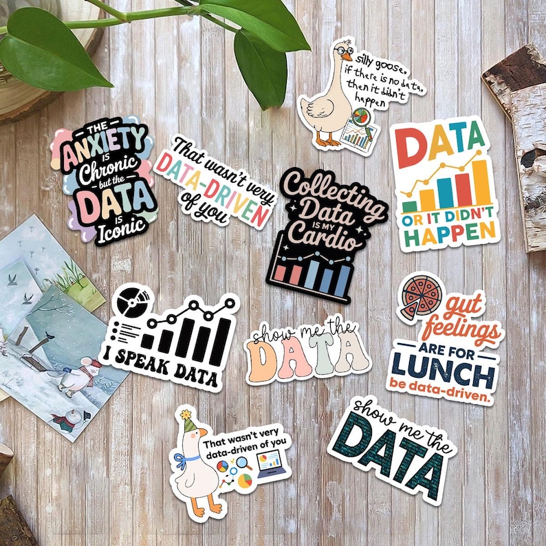 Puede incluir: Una colecci&oacute;n de pegatinas coloridas con frases y gr&aacute;ficos relacionados con datos. Las pegatinas presentan frases como "Collecting Data is my Cardio" y "Show me the Data". Las pegatinas est&aacute;n sobre una superficie de madera.
