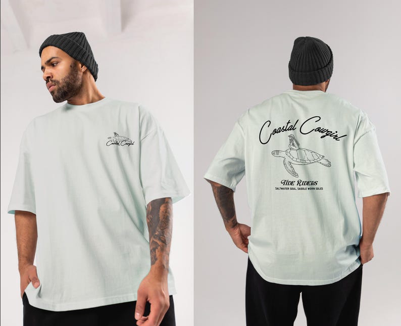 May include: A light blue t-shirt with a graphic of a sea turtle and the text "Coastal Cowgirl Tide Riders Saltwater Soul, Saddle Worn Sole" printed on the front.